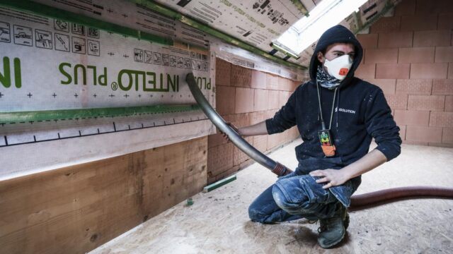 Ouvrier Isolution réalisant l'isolation des murs par l'intérieur par insufflation avec pare-vapeur Intello Plus