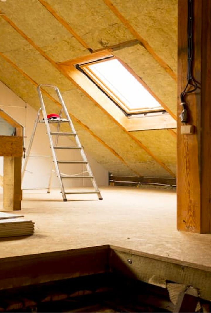Photo d'un plafond de toiture recouvert de panneaux isolants semi rigides, une échelle est posée au sol sous une fenêtre